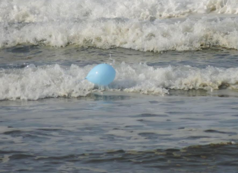 A rubber balloon coming ashore on the surf. 