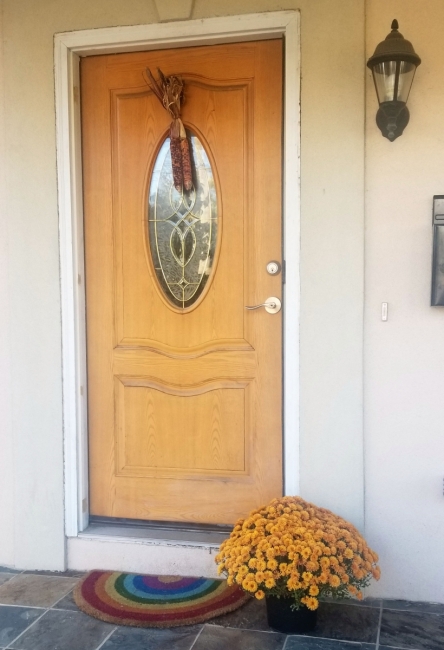 Pumpkins, dried corn, and other natural materials used to decorate a front door.