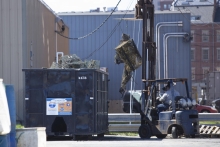 A person uses a forklift to place old fishing nets into a dumpster.