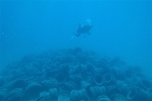 A SCUBA diver swims over a pile of tires located on the ocean floor near Hawaii.