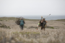 Man and woman carry debris through an open field. 