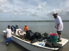 The four person field crew of commercial watermen on a boat full of collected marine debris. 