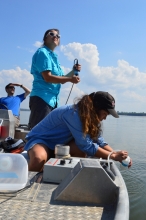 Three scientists collect water data from a boat.