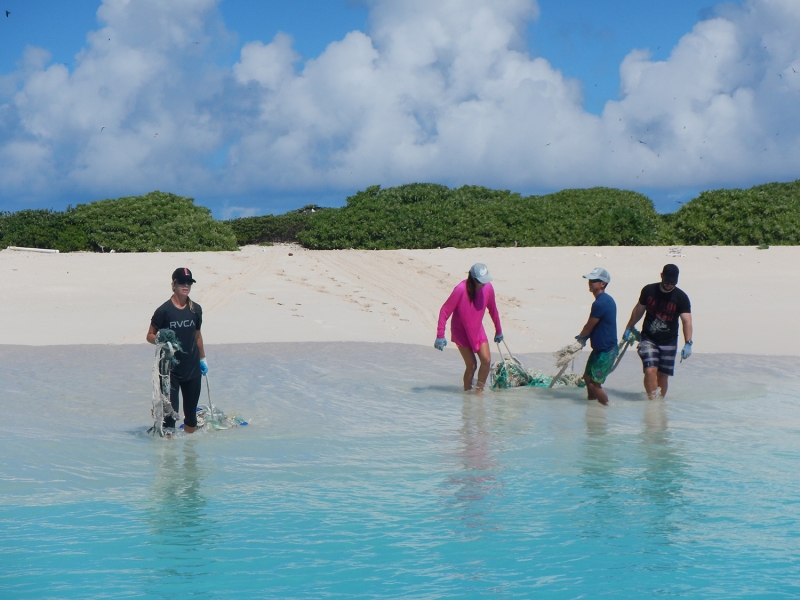 Kristen, Liat, Ryan, and David wrestle fishing nets through the shallow water, away from the shores of Lisianski Island, to be collected in the inflatable small boats for removal.