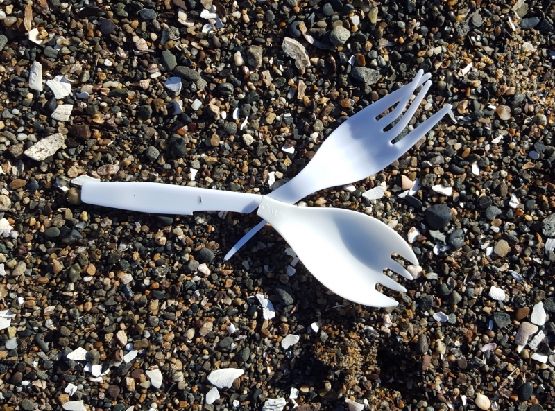 Two plastic forks on course sand.