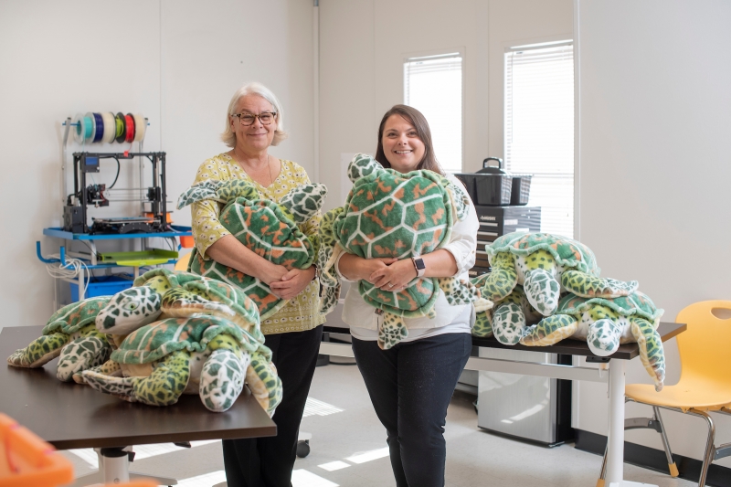 Program staff pose with stuffed turtles. 