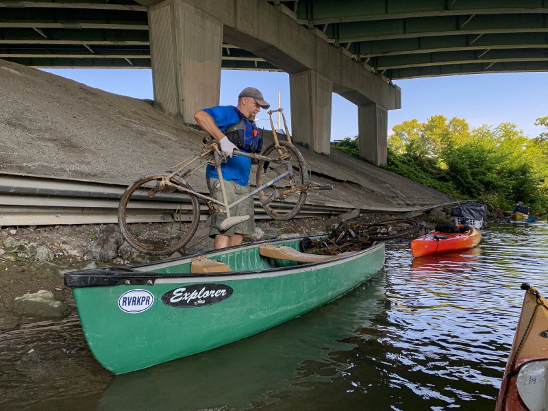 A person loads an old bike into a green canoe in Ohio.