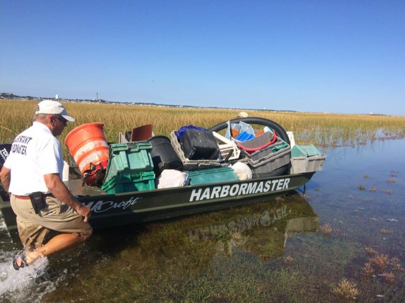 A person guides a boat filled with debris through a marsh.