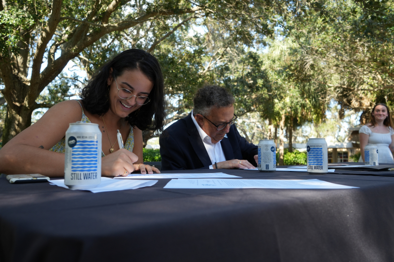 School leaders signing a document at an outdoor event.
