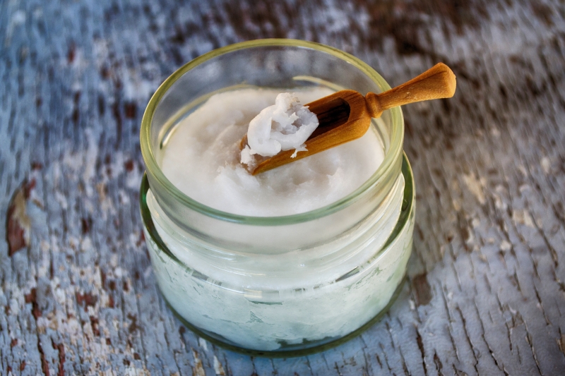 A jar filled with coconut oil with a small scoop.