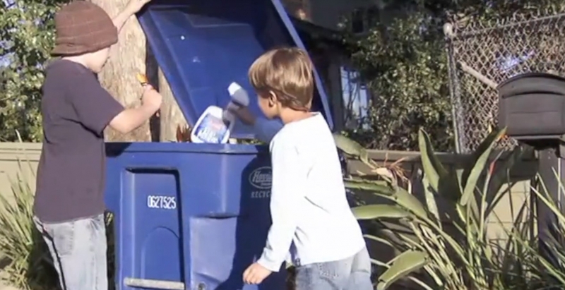 Kids putting bottles into a recycling bin.