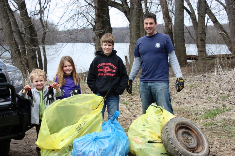 Three children and an adult behind a pile of trash. 