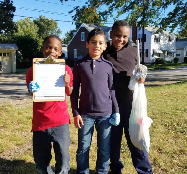 Three boys holding equipment for a cleanup.
