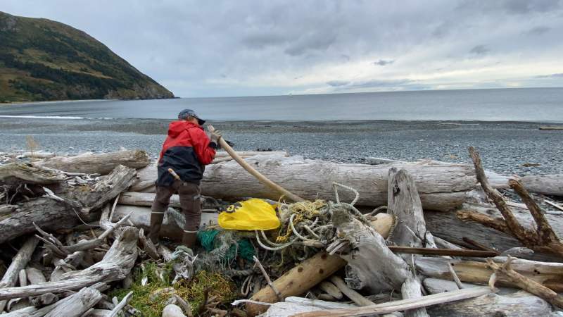 A volunteer removes a net and other marine debris from the shore. 