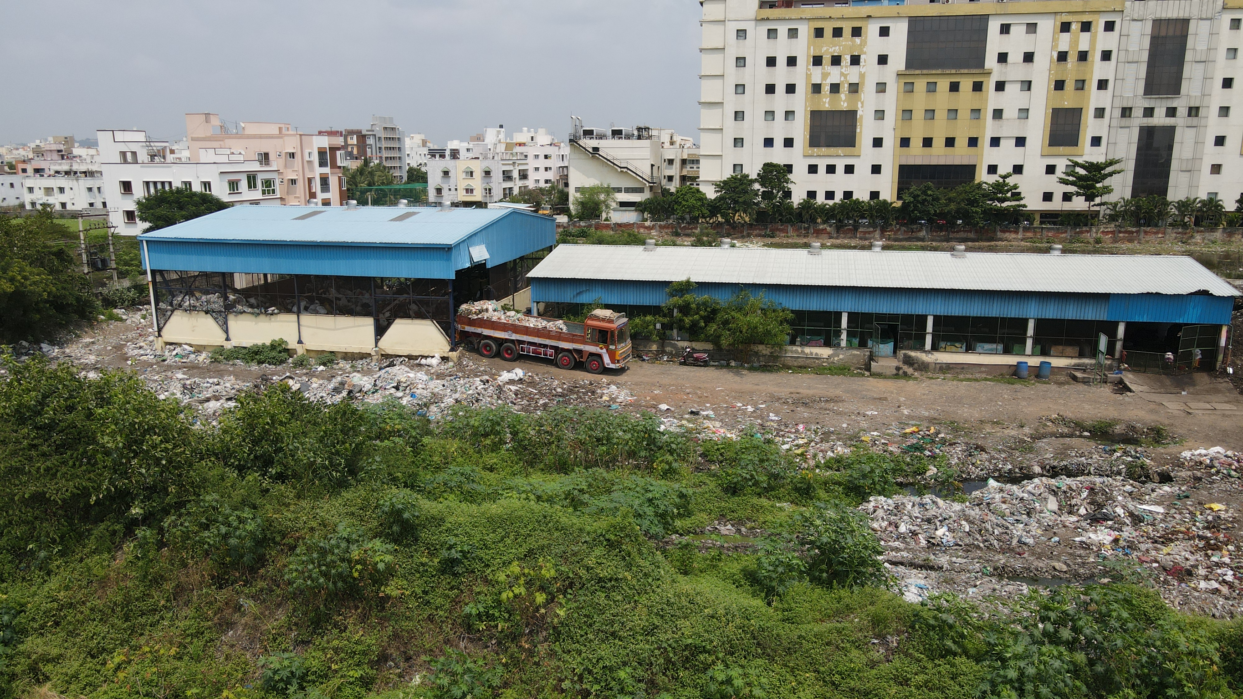 A trash sorting center with a truck backing in a full load of trash in Chennai, India.