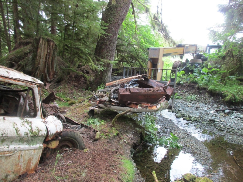 An abandoned vehicle being removed with a forklift from a stream. 