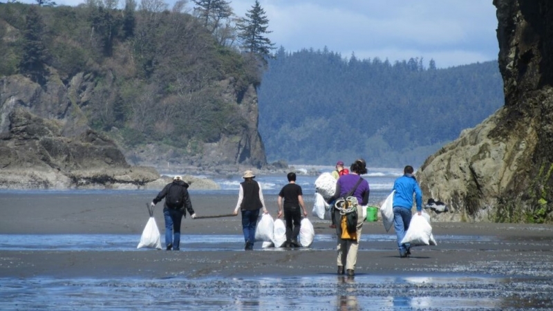 A group of people hauling marine debris off a beach.
