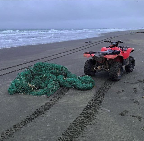 A removed derelict net on the beach next to an all-terrain vehicle.