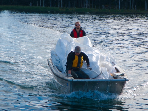 Two volunteers in a skiff moving bags of marine debris.