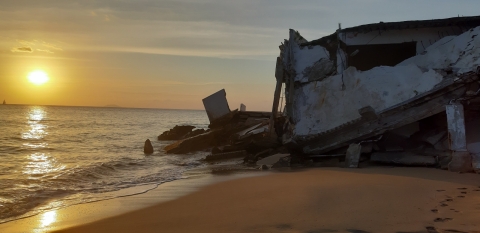 A collapsed structure on an ocean beach shoreline.