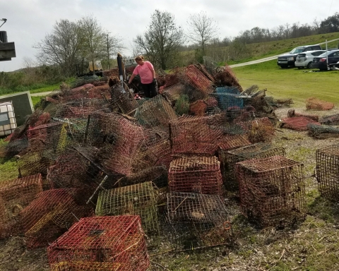 Two people stand to look at a huge pile of collected crab pots.