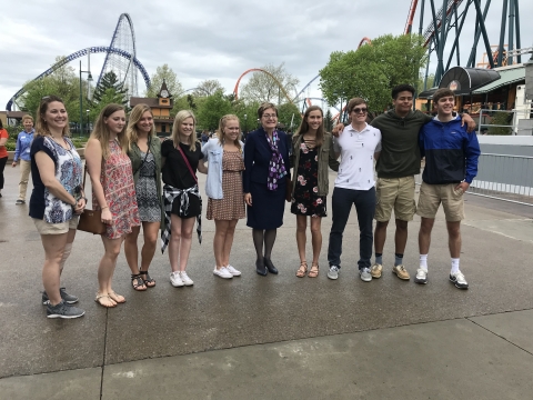 A group standing together in front of roller coasters.