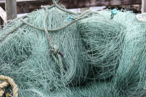 A very large, derelict fishing net on land.