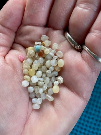 An open hand with a pile of small plastic pellets.