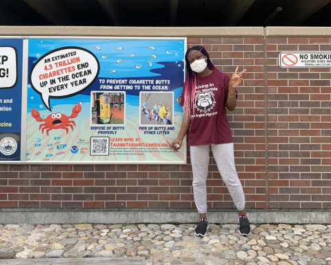 A student posing next to a cigarette debris prevention poster.