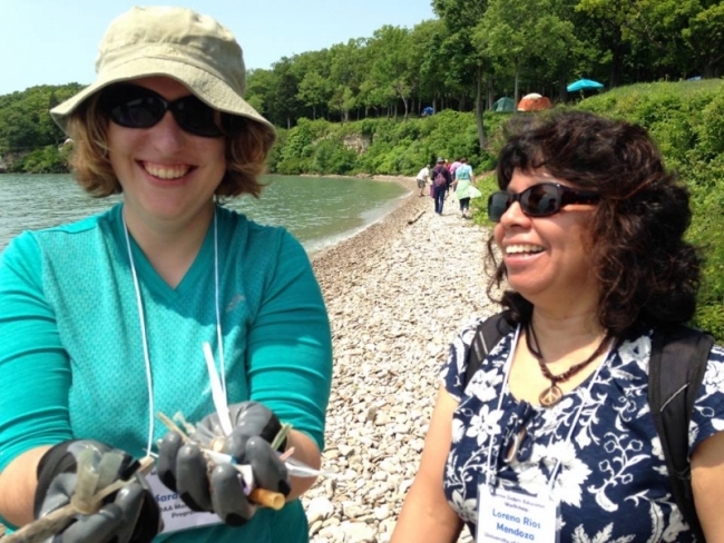Two women hold up items collected on the coast of Lake Erie.