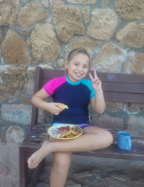 A girl sits, eating food.