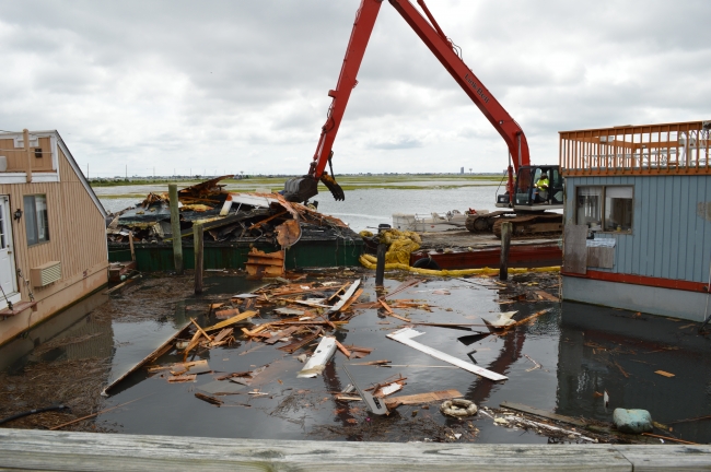 A crane moving floating debris into a floating dumpster.
