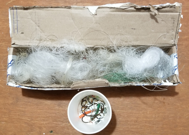A box of used fishing line and a container of old hooks.