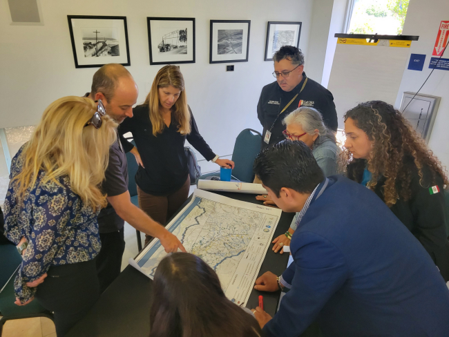 A group of people standing around a table looking at a map.