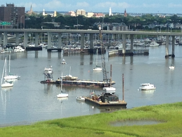 View from above of a salvage company removing several abandoned and derelict vessels along the bank of the marsh. 