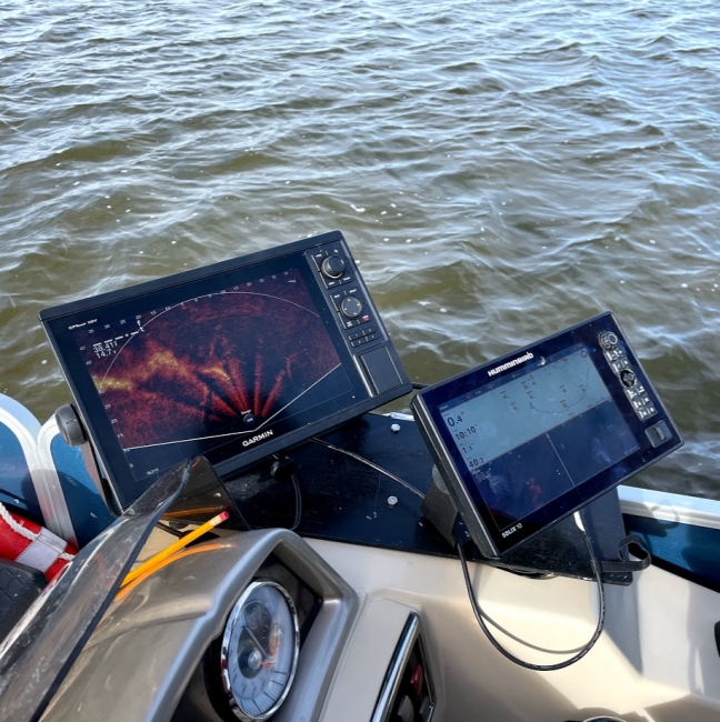 Side-scan and live sonar screen devices mounted on a survey vessel.