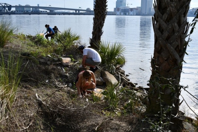 Students collecting debris along a shore.
