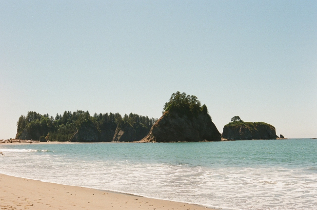 A picture of the shoreline and rocky islands topped with trees in the distance.