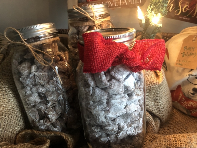 A glass jar is filled with powdered sugar-covered cereal and tied with a red bow. 