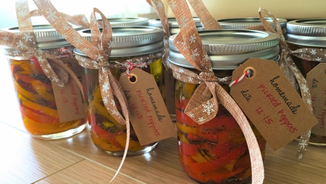 Seven glass jars are filled with sliced peppers and tied with a bow, affixed with a paper tag.