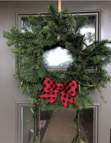 A wreath made of tree trimmings and decorated with a lei.
