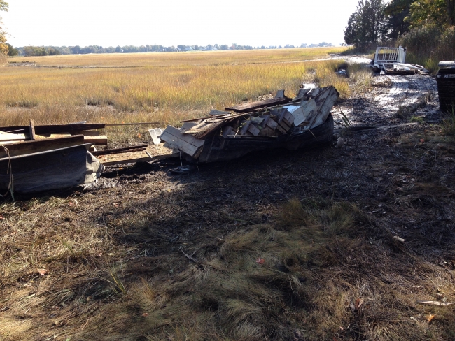 Containers of large debris being dragged to move them out of a marsh.