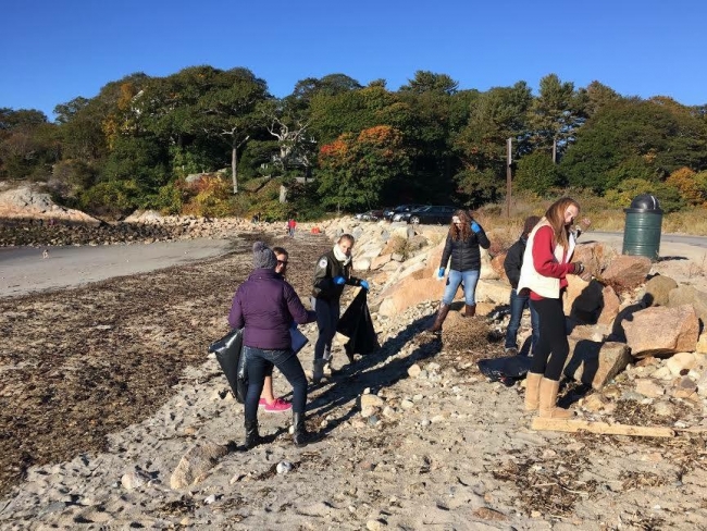 Students picking up trash on a beach.