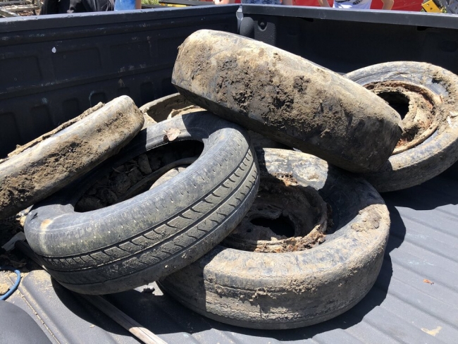 A pile of old tires in the bed of a truck.