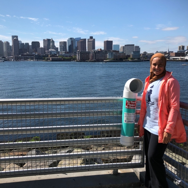 A person stands next to a bin with the Boston skyline in the background.