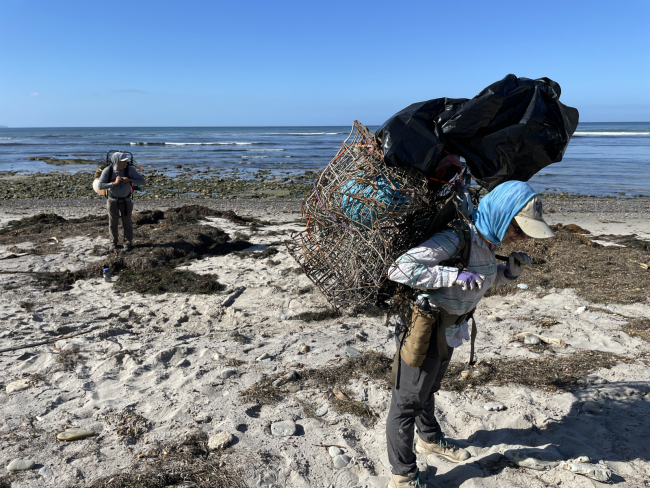 Volunteers carry marine debris on their backs to hike out.