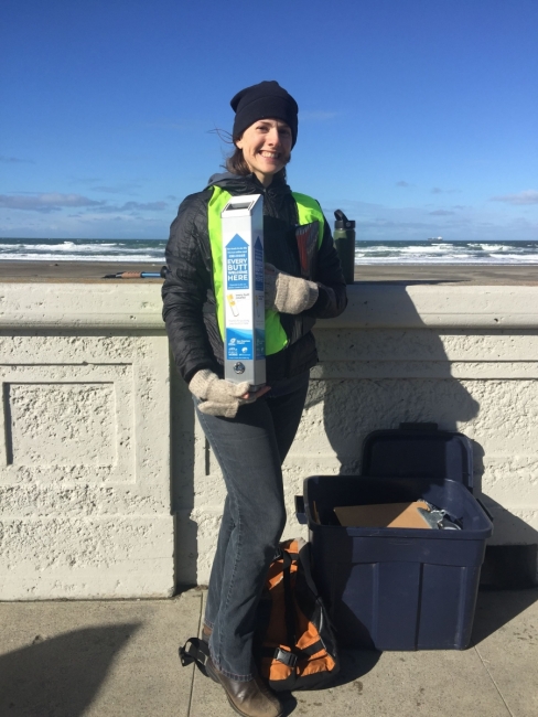 Shelly Ericksen holds up a buttcan in front of Ocean Beach.