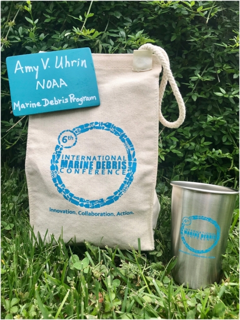 A reusable cotton lunch bag, wooden name tag, and metal cup.