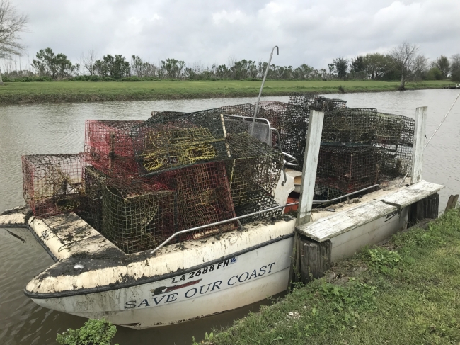 A small vessel tied to shore is full of collected and discarded crab traps.