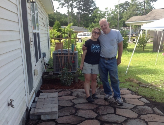 Daughter and father pose on patio they built together. 